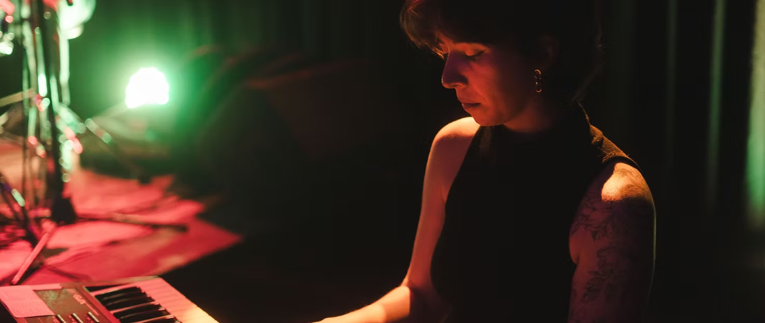Paulina tocando el teclado en un escenario iluminado